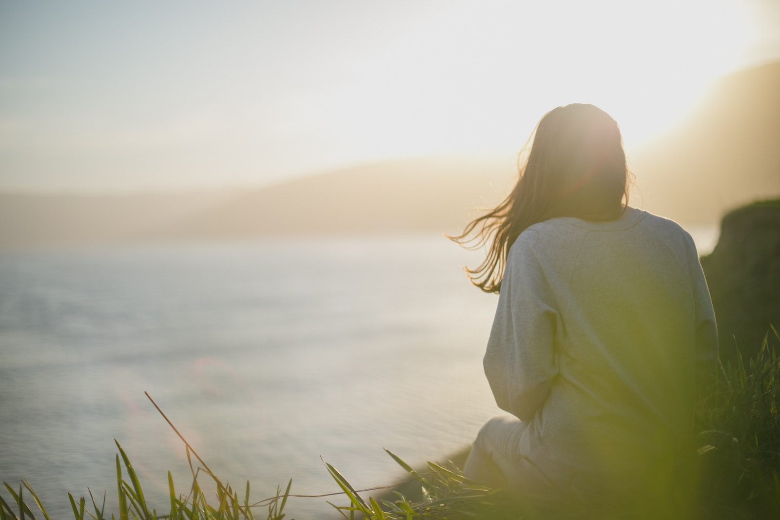 Photo par Artem Kovalev woman wearing gray long-sleeved shirt facing the sea